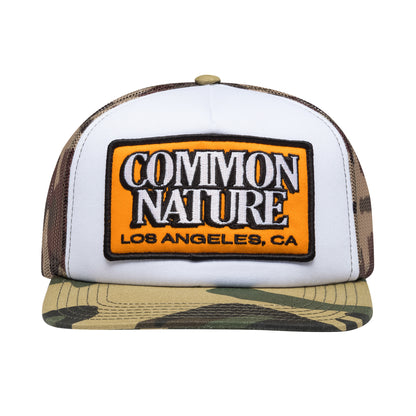 Common Patch Hat in camo, front view with orange Common Nature patch and camo mesh