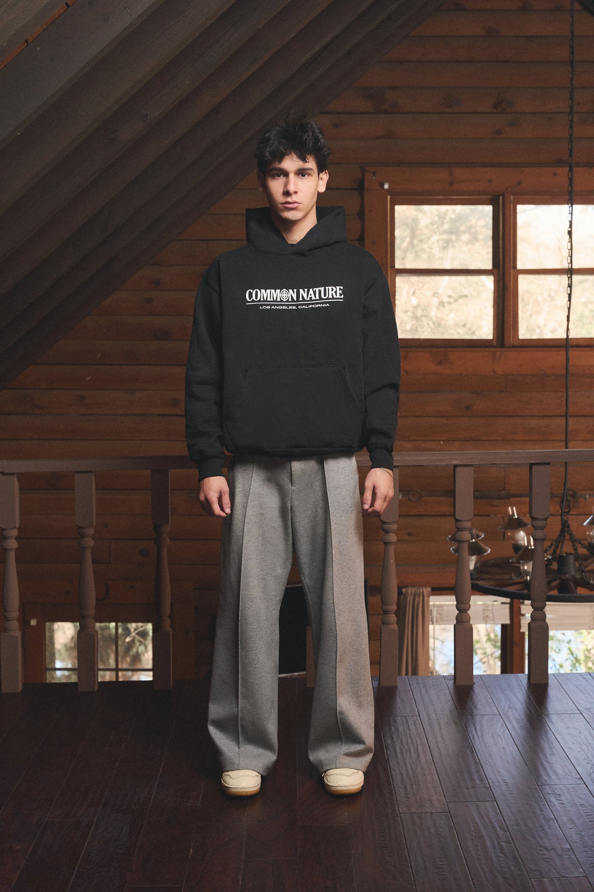 Man in a black Common Nature hoodie in a cabin loft